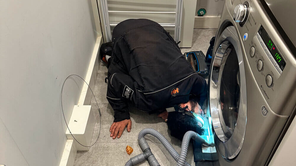 Barton technician cleaning a washer drain pump filter in Vancouver