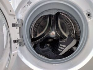 Washing dark sneakers inside an open front-load washing machine.